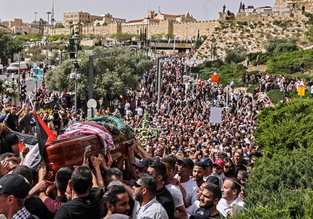 Para pelayat wartawan Al Jazeera Shireen Abu Akleh yang tewas ditembak Israel beriring memadati jalan saat membawa jenasah Aqleh dari gereja menuju ke pemakaman di Jerusalem, 13 Mei 2022. 