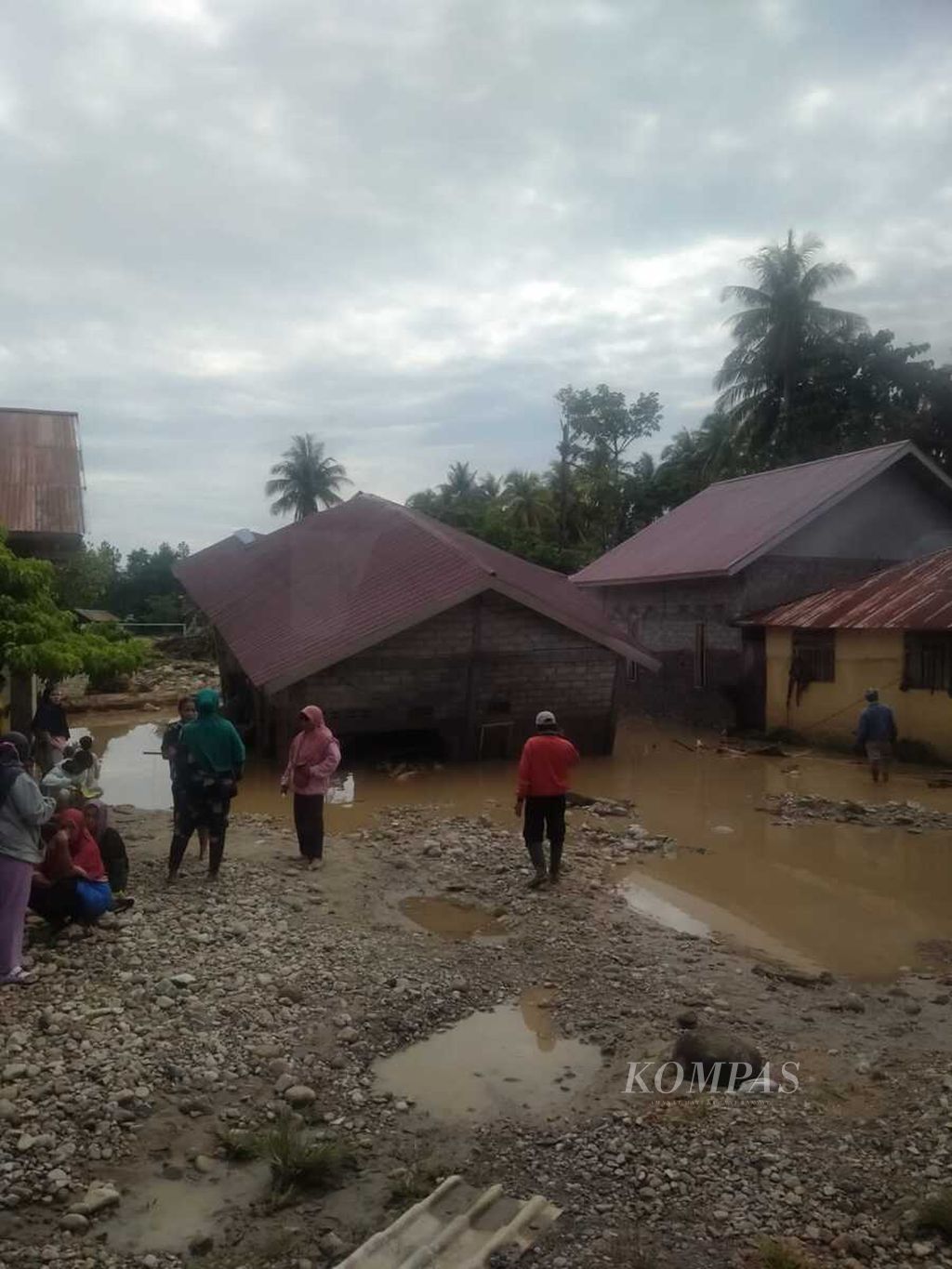 Warga Desa Torue, Kecamatan Torue, Kabupaten Parigi Moutong, Sulteng, Jumat (29/7/2022), berada di sekitar rumah mereka yang dilanda banjir bandang pada Kamis (28/7/2022). Banjir bandang tersebut menewaskan tiga orang, sementara empat orang lainnya masih dicari.