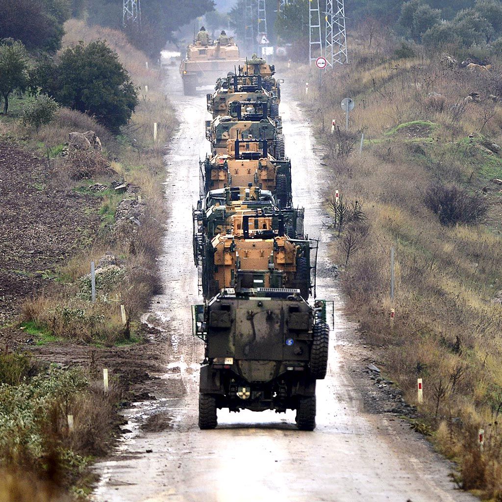 Konvoi kendaraan lapis baja pengangkut personel milik militer Turki di pinggiran kota Hassa, Turki, sedang  berjalan menuju perbatasan Suriah, Selasa (23/1).