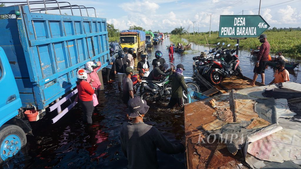 Banjir menutup jalan Trans-Kalimantan di wilayah Bukit Rawi, Kabupaten Pulang Pisau, Selasa (5/5/2020). Pengguna motor terpaksa menggunakan jasa dadakan kapal bermotor atau kelotok untuk melewati kemacetan.