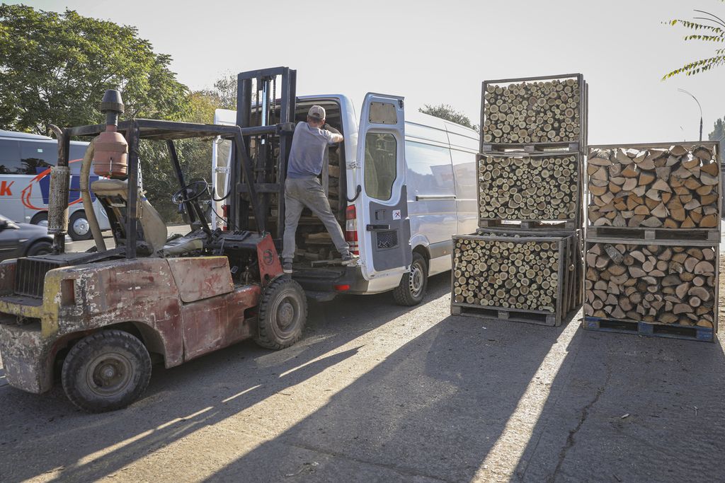 Dua pekerja tengah memasukkan kotak yang berisi kayu bakar yang telah dipotong ke dalam sebuah minivan di pinggir ibu kota Moldova, Chisinau, Sabtu (15/10/2022). Dengan harga gas meningkat hingga enam kali lipat, warga Moldova mulai menggunakan kayu bakar sebagai pengganti gas. 