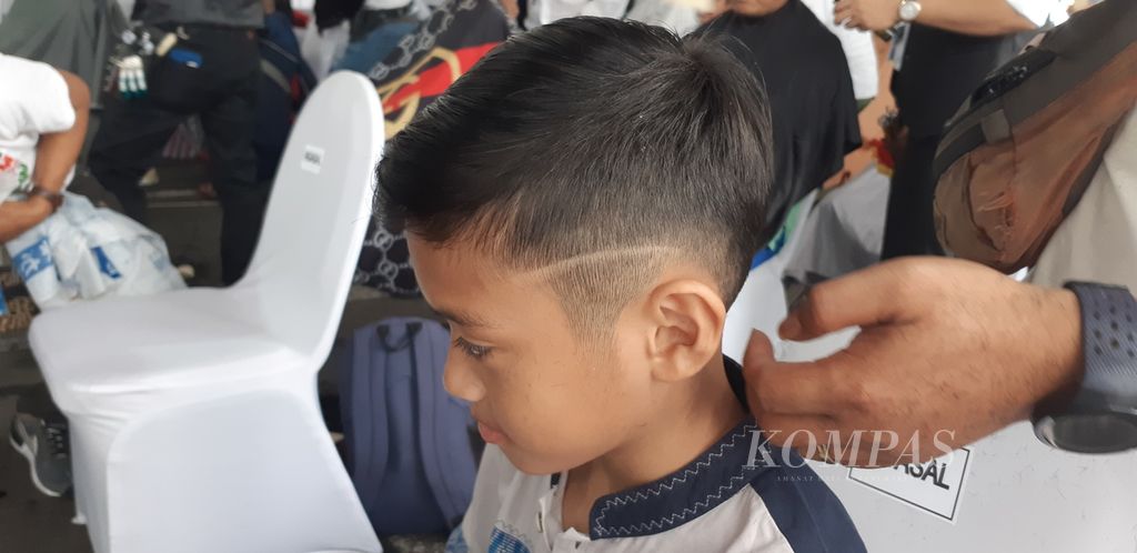 Seorang anak memilih dipotong rambutnya dengan gaya <i>under cut</i> dalam kegiatan potong rambut gratis yang menjadi bagian dari Frstival Ramadhan 2024 di Masjid Al Akbar Surabaya, Kota Surabaya, Jawa Timur, Senin (11/3/2024).
