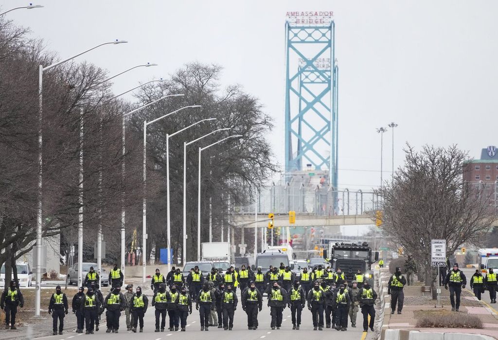 Polisi Kanada mulai bersikap tegas dengan membubarkan aksi pengemudi truk dan pendukung mereka yang dalam sepekan terakhir memblokir akses Jembatan Ambassador di Windsor yang menghubungkan Windsor dan Detroit, Amerika Serikat, Minggu (13/2/2022). 