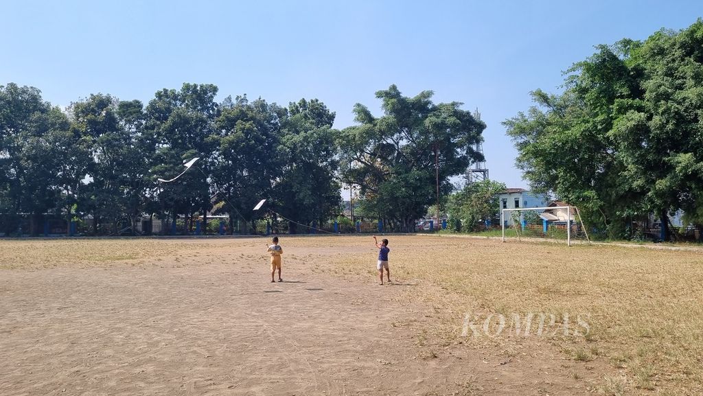 Dua anak bermain layang-layang di Lapangan Sampo, Kota Malang, Jawa Timur, Selasa (25/7/2023). Lapangan yang awalnya didirikan untuk membantu pembinaan sepak bola usia dini kini sudah tidak terawat dengan baik.