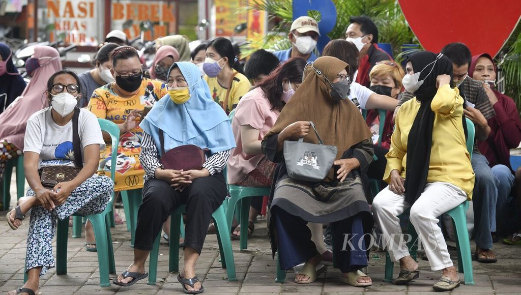  Residents wait their turn while participating in the Covid-19 vaccination at the Cipondoh Indah Village Office, Cipondoh, Tangerang City, Banten, Monday (7/3/2022). The vaccination is a requirement for residents who will buy cooking oil and buffalo meat in market operations in the same location. Indonesia appears to have passed the peak of the surge in Omicron cases.