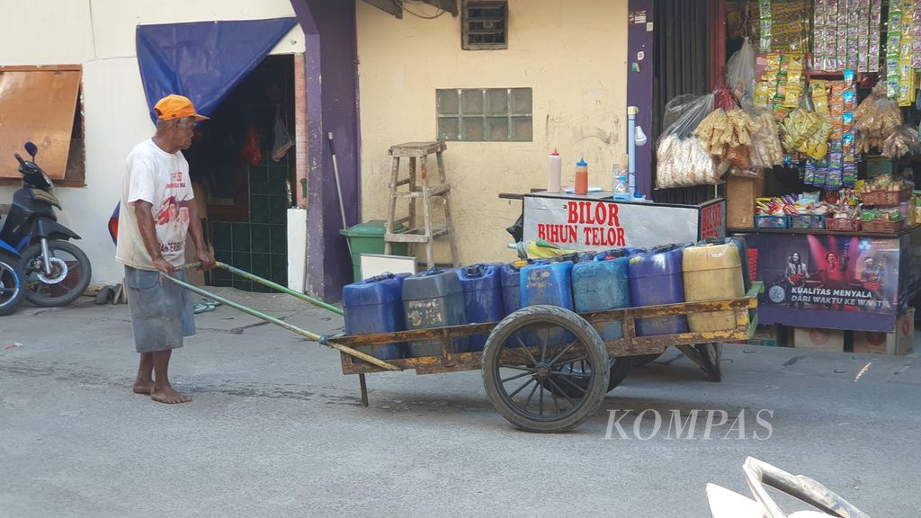 Penjual air keliling mendorong gerobaknya untuk menjajakan air bersih kepada warga Kampung Gedung Pompa RT 020/RW 017, Kelurahan Penjaringan, Kecamatan Penjaringan, Jakarta Utara.