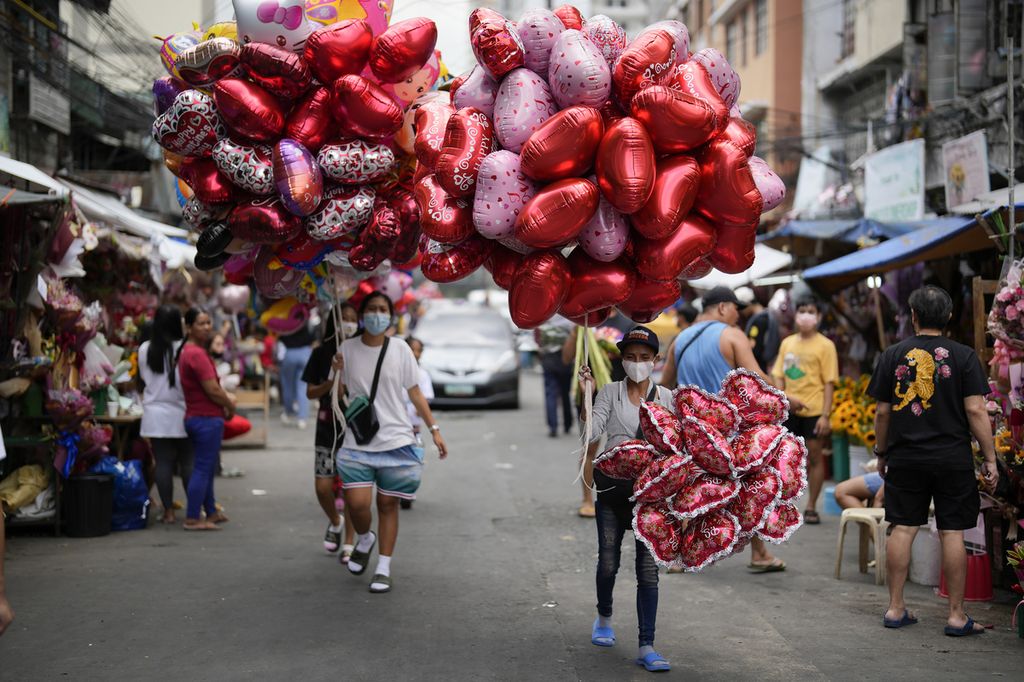 Seorang perempuan menjual balon berbentuk hati di pasar bunga di Manila, Filipina, Senin (13/2/2024). 