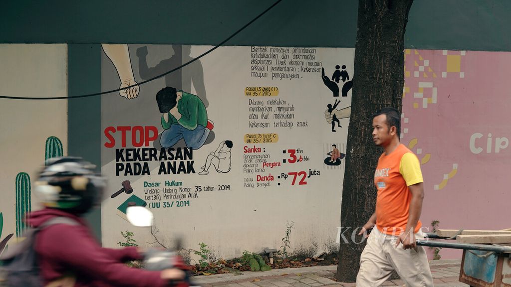 Warga melintasi mural hentikan kekerasan pada anak di Pulo Gadung, Jakarta Timur, Kamis (17/3/2022).