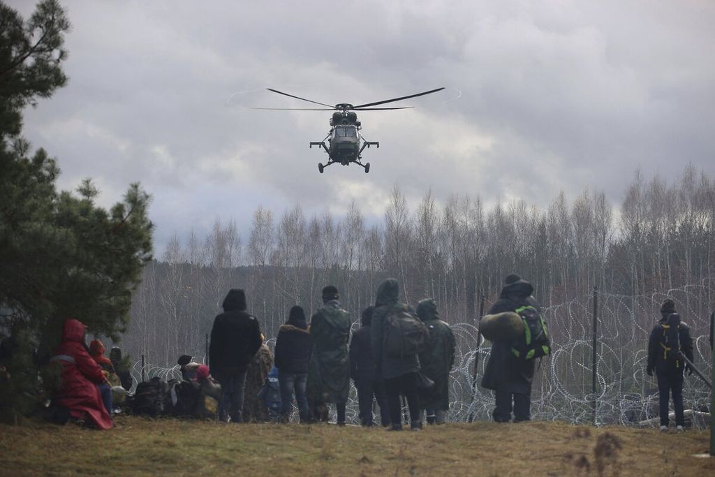 Sebuah helikopter milik militer Polandia terbang di atas sekelompok imigran dari Timur Tengah di perbatasan Polandia-Belarusia AP/BELTA/LEONID SCHCEGLOV