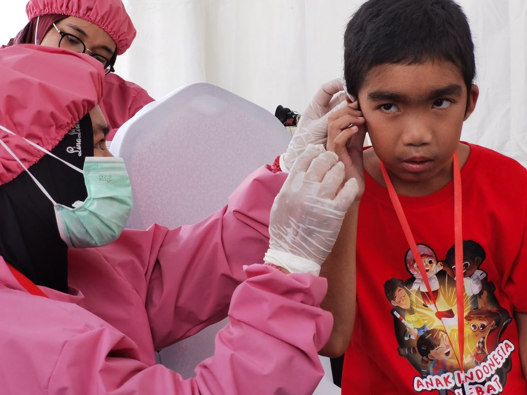 Anggota tim Alat Bantu Dengar Indonesia (ABDI) memasang alat bantu dengar untuk Lalu Akdan Syafiq Iskandar (11) dalam peringatan Hari Anak Nasional 2022 di Selong, Lombok Timur, Nusa Tenggara Barat, Senin (1/8/2022). 