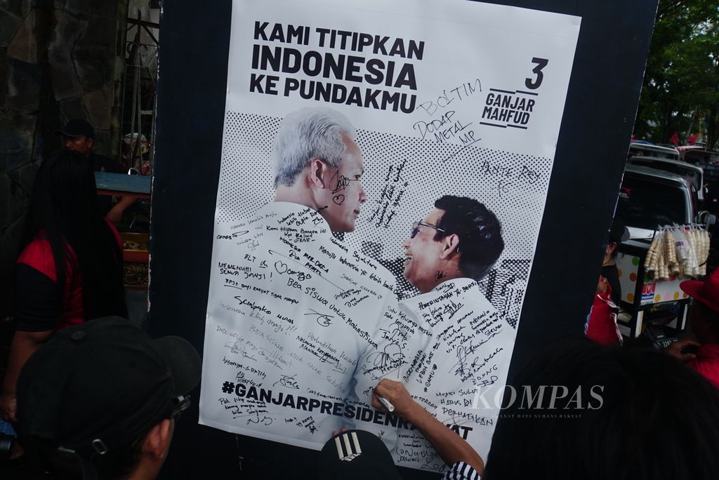 Simpatisan pasangan calon presiden dan calon wakil presiden nomor urut 3, Ganjar Pranowo dan M Mahfud MD, menandatangani poster pasangan calon dukungannya di gerbang Lapangan KONI Sario, Manado, Sulawesi Utara, Kamis (1/2/2024). 