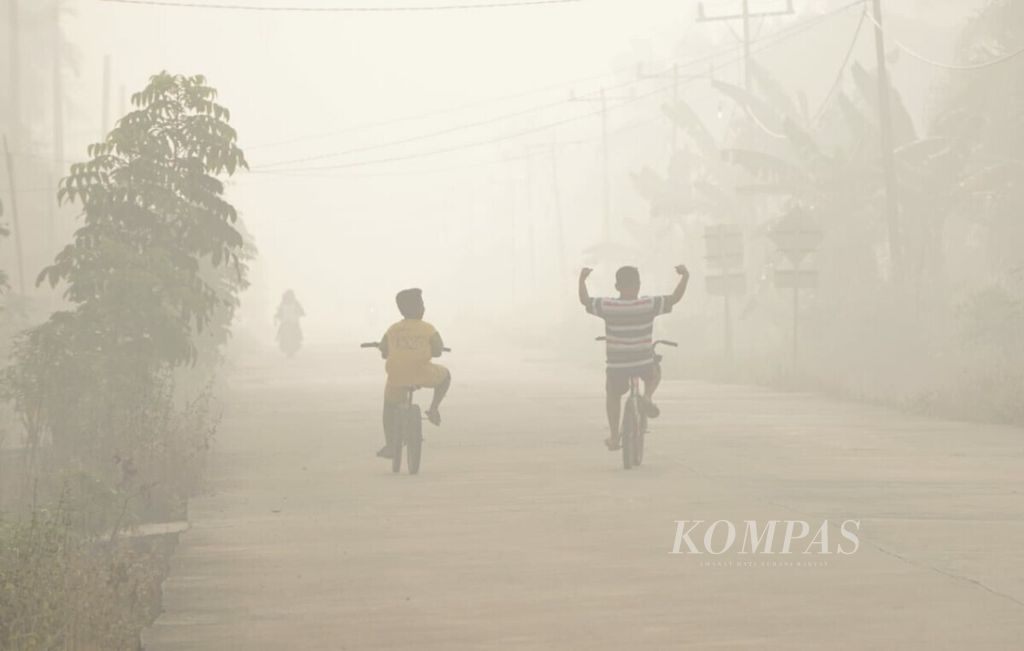 Warga menerobos kabut asap di Desa Sei Rampai, Kecamatan Rupat, Kabupaten Bengkalis, Riau, Minggu (24/2/2019).