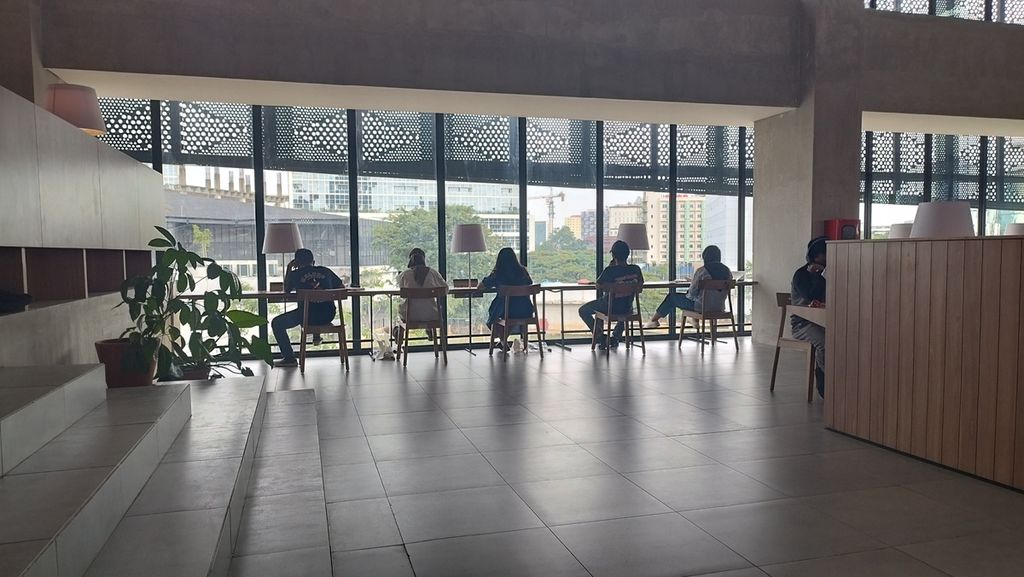 Sejumlah orang tengah membaca buku sembari menghadap ke luar gedung Perpustakaan Umum DKI Jakarta, Senin (30/1/2023).