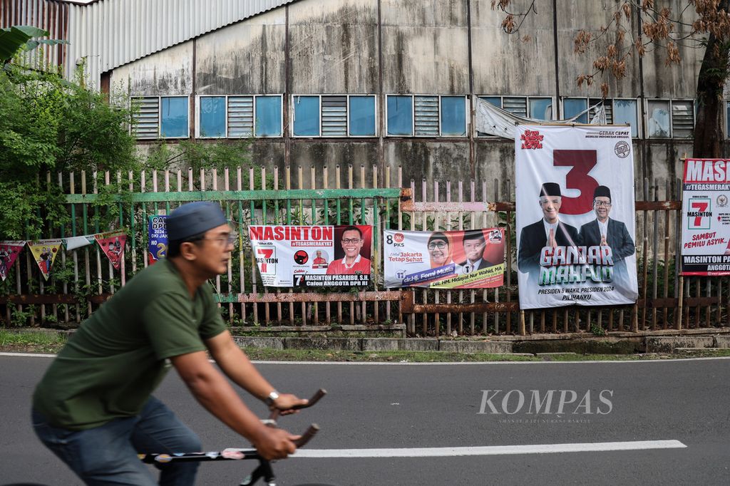 Pesepeda melintas di depan deretan spanduk peserta Pemilu 2024 yang dipasang di Jalan Duren Tiga Selatan, Jakarta, Selasa (5/12/2023).