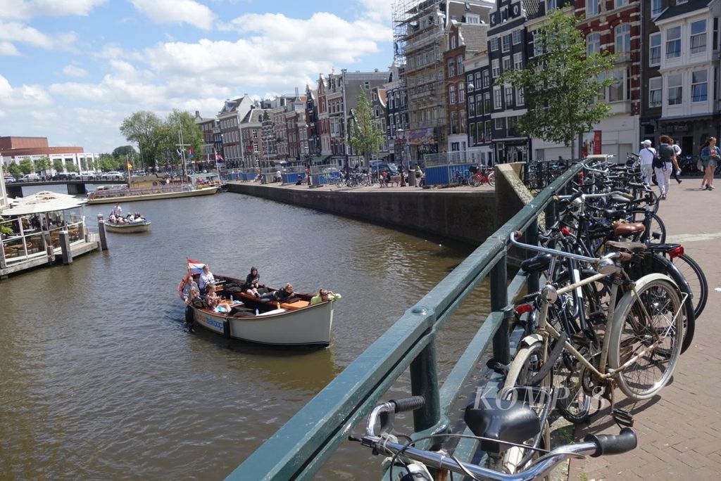 Sepeda, kanal, perahu, dan deretan bangunan khas di Amsterdam, Belanda. Kota ini dijuluki ibu kota sepeda dunia”.