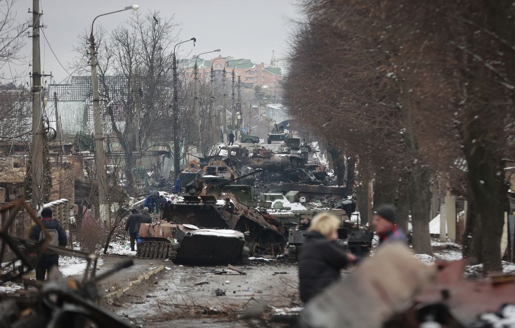 Warga melihat kendaraan militer Rusia yang hancur di jalanan kota Bucha, dekat ibu kota Kiev, Ukraina, 1 Maret 2022. Sejumlah perusahaan teknologi ikut menghukum Rusia dengan menghentikan berbagai layanan di negara tersebut setelah Rusia melakukan serangan militer ke Ukraina.  