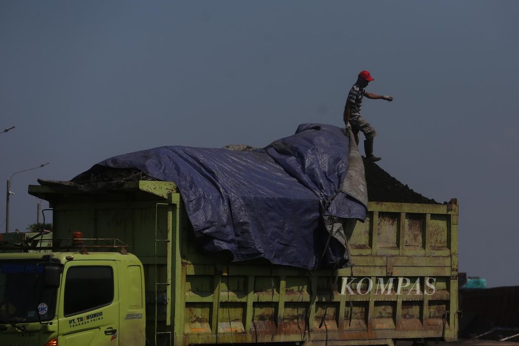 Pekerja menutup batubara asal Kalimantan dengan terpal di Pelabuhan KCN, Marunda, Jakarta Utara, Rabu (5/1/2022). Pemerintah kini akan mewajibkan setiap eksportir batubara untuk memenuhi kebutuhan batubara dalam negeri (DMO) sebesar 25 persen dari total produksi tahunan setiap mereka hendak mengekspor batubara. 