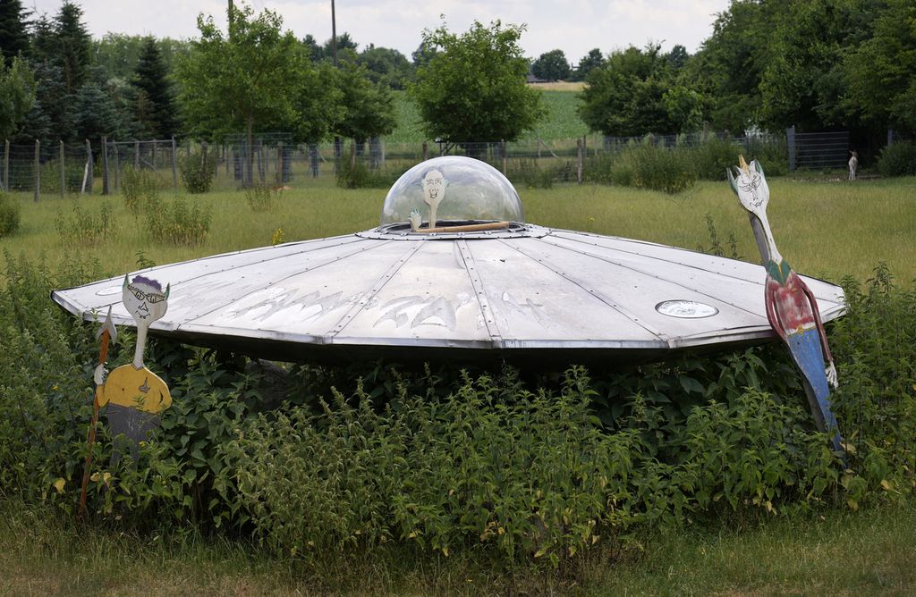 Sebuah tiruan benda terbang tak dikenal (UFO) dan tiga alien tiruan dipasang di sebuah taman di Jacobsdorf, Jerman, 25 Juni 2021.