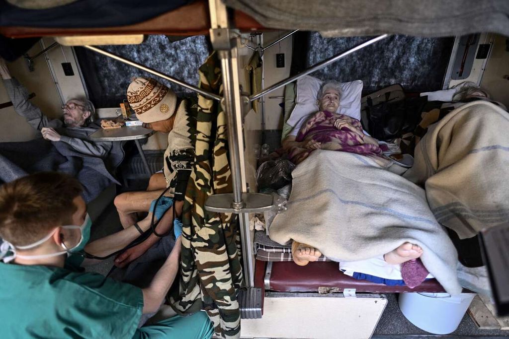 Pasien yang menjalani perawatan ditempatkan di kursi kereta evakuasi medis dalam perjalanan ke kota Lviv, Ukraina barat, Minggu (10/4/2022). 