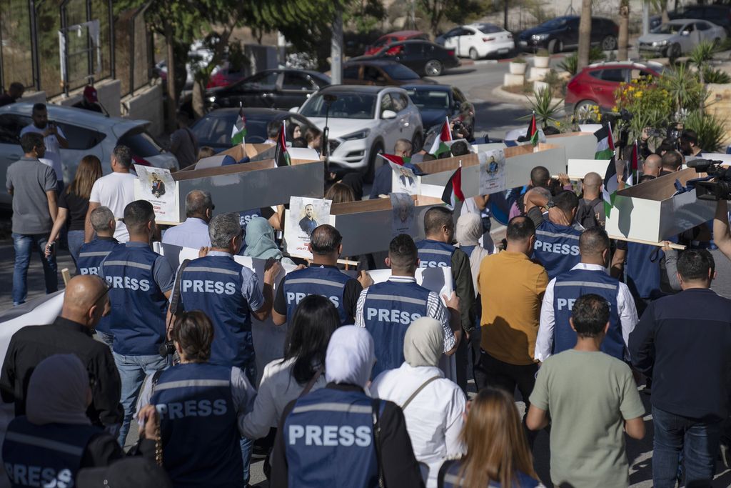 Wartawan-wartawan Palestina membawa tiruan peti mati jurnalis Palestina yang terbunuh dalam perang di Gaza saat pemakaman simbolis menuju kantor PBB, di kota Ramallah, Tepi Barat, Selasa (7/11/2023). Asosiasi Jurnalis Palestina menyampaikan, ada 30 wartawan Palestina yang terbunuh sejak serangan 7 Oktober 2023. 