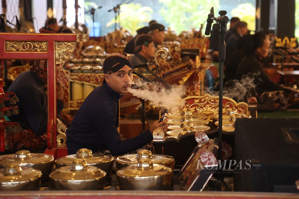 A palace servant used an electric cigarette while waiting to play the gamelan during a wayang golek performance at the Srimanganti Bangsal of the Yogyakarta Palace, Yogyakarta, on Wednesday (1/3/2023). Electric cigarettes are just as harmful as conventional cigarettes because they contain many chemical compounds that have a negative impact on the body, some of which are carcinogenic or can trigger cancer.