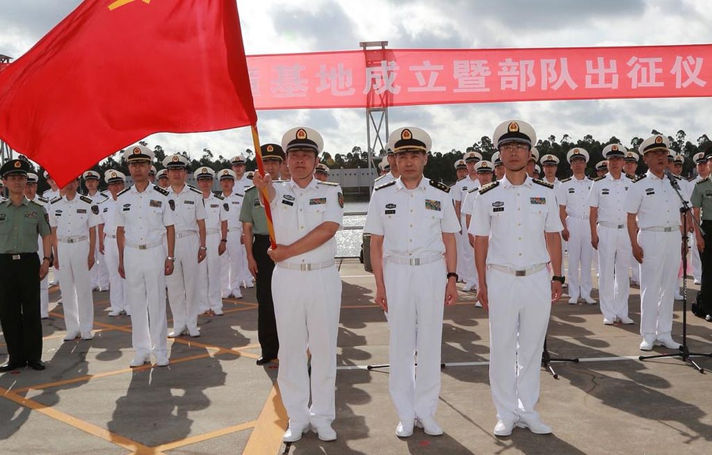 Seorang anggota Tentara Pembebasan Rakyat China (PLA) memegang bendera PLA sementara anggota militer lainnya berbaris di sebuah pelabuhan militer di  Zhanjiang, Provinsi Guangdong, China, Selasa (11/7/2017).