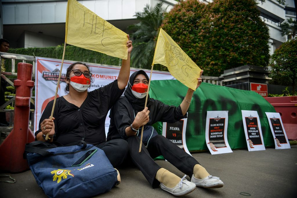 Dua peserta aksi duduk sembari mengibarkan bendera kuning sebagai tanda kekecewaan mereka kepada Kementerian Kesehatan (Kemenkes) saat melakukan aksi di depan Kantor Kemenkes, Jakarta Pusat, Senin (29/5/2023).