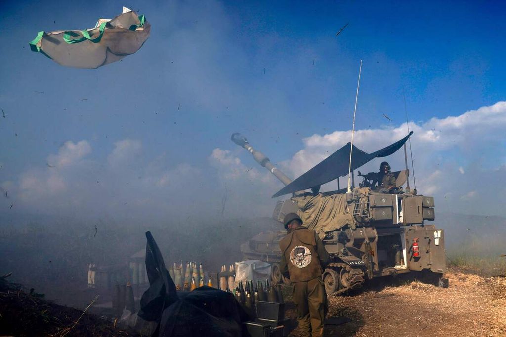 Seorang tentara Israel memakai tambalan bergambar wajah Pemimpin Hezbollah Sheikh Hassan Nasrallah dengan tanda sasaran target pada bagian belakang jaketnya di depan sebuah tank di Dataran Tinggi Galilee, Israel utara, 4 Januari 2024. 