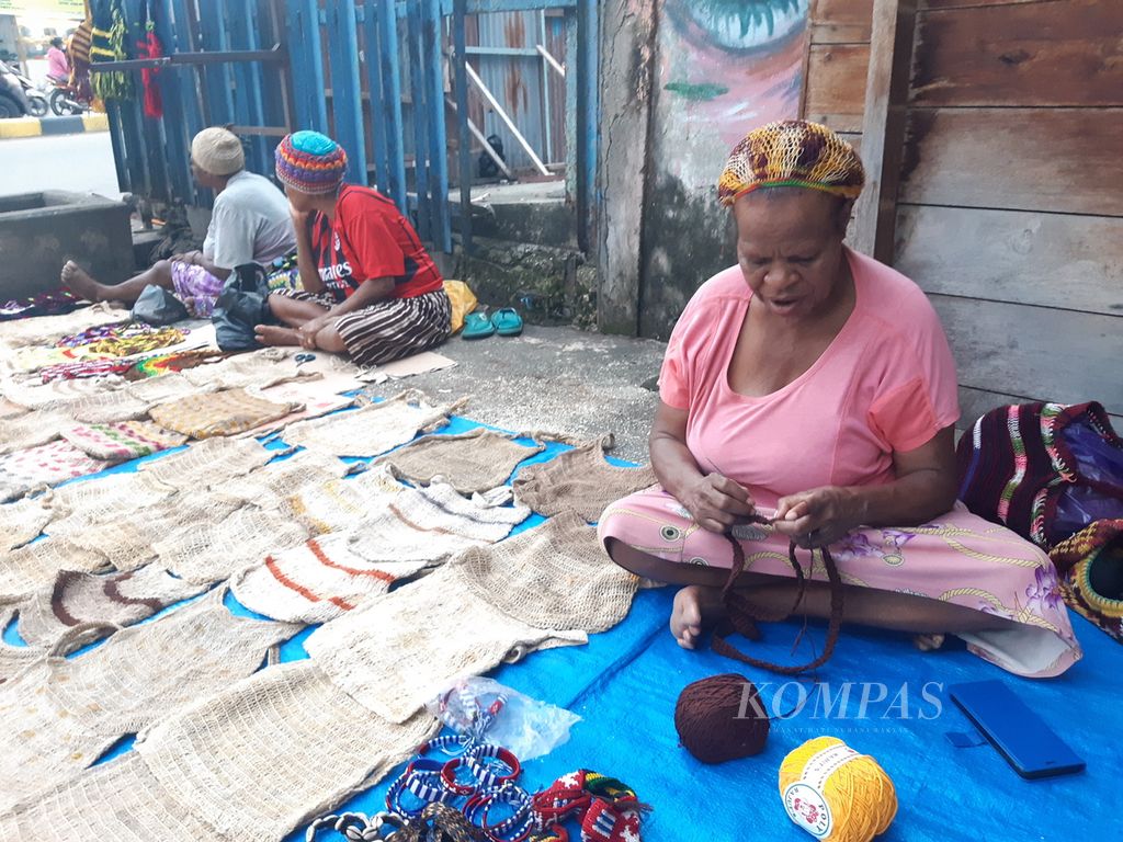 Ketua Kelompok Noken Kreatif Maria Ukago (baju merah jambu) merajut tas noken dari benang. Biasanya wanita berusia 55 tahun ini melakukan aktivitas merajut sambil menunggu pembeli di tempat jualannya di Distrik Abepura, Kota Jayapura, Papua, 28 Agustus 2023.
