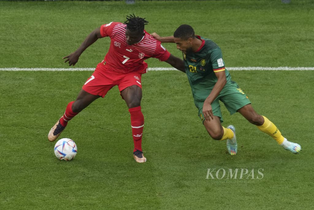 Pemain Swiss, Breel Embolo (kiri), berebut bola dengan Jean-Charles Castelletto dari Kamerun saat bertanding di babak fase Grup G Piala Dunia 2022 di Stadion Al Janoub, Qatar, Kamis (24/11/2022). Swiss menang 1-0.