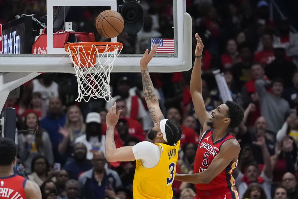 Los Angeles Lakers player, Anthony Davis (left), throws the ball under the challenge of New Orleans Pelicans player, Herbert Jones (right/5), during an NBA playin game, Wednesday (17/4/2024) morning Indonesian time, in New Orleans. The Lakers won with a score of 110-106.