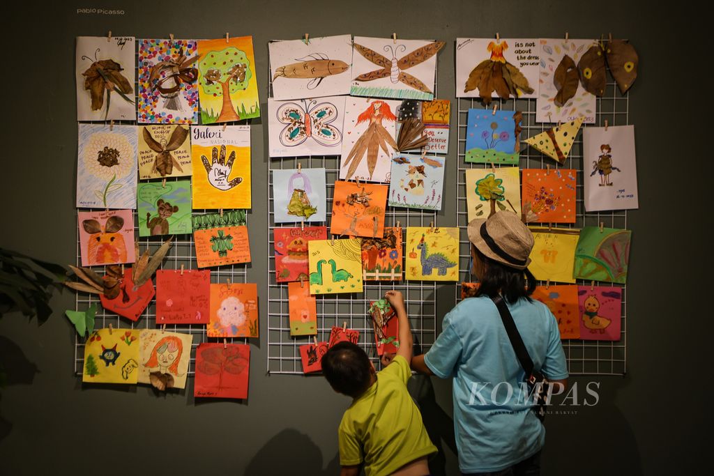 Seorang anak menempel lukisannya di ruang aktivitas anak dan keluarga dalam rangkaian pameran Seni Rupa Indonesia Kini: Pascamasa di Galeri Nasional Indonesia, Jakarta, Jumat (29/12/2023). 