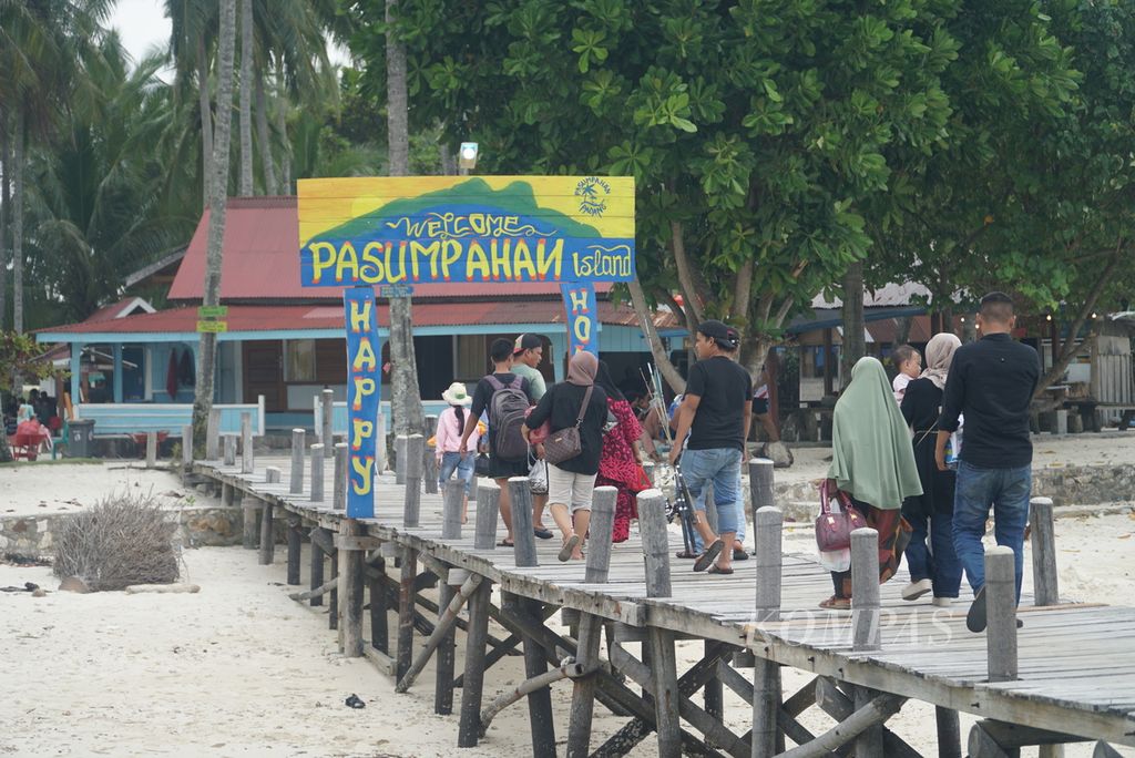 Rombongan pengunjung berjalan dari dermaga menuju Pulau Pasumpahan, Kelurahan Teluk Kabung Selatan, Kecamatan Bungus Teluk Kabung, Kota Padang, Sumatra Barat, Minggu (8/10/2023). 
