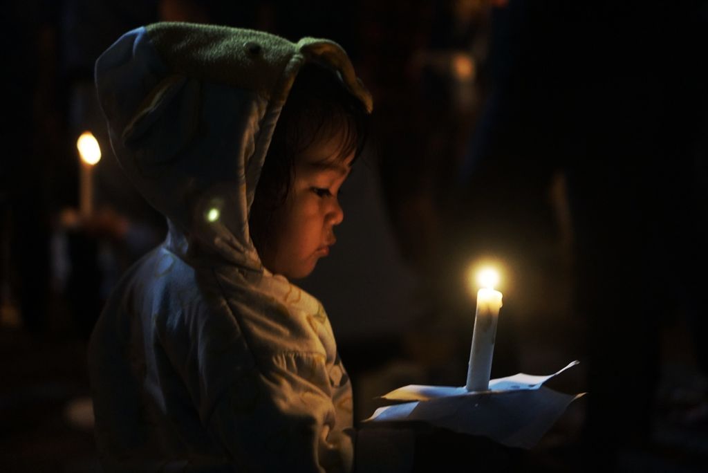 Seorang anak melihat lilin yang ia bawa dalam doa bersama di Kota Balikpapan, Kalimantan Timur, Selasa (3/10/2022) malam. Ratusan pencinta sepak bola berkumpul dan berdoa bersama bagi ratusan korban akibat tragedi di Stadion Kanjuruhan, Malang, Jawa Timur.