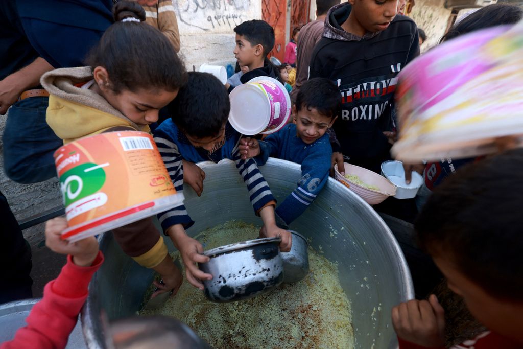 Anak-anak pengungsi Palestina mengumpulkan makanan di tempat sumbangan yang disediakan kelompok amal di kota Rafah di Jalur Gaza selatan, pada 6 Desember 2023. 