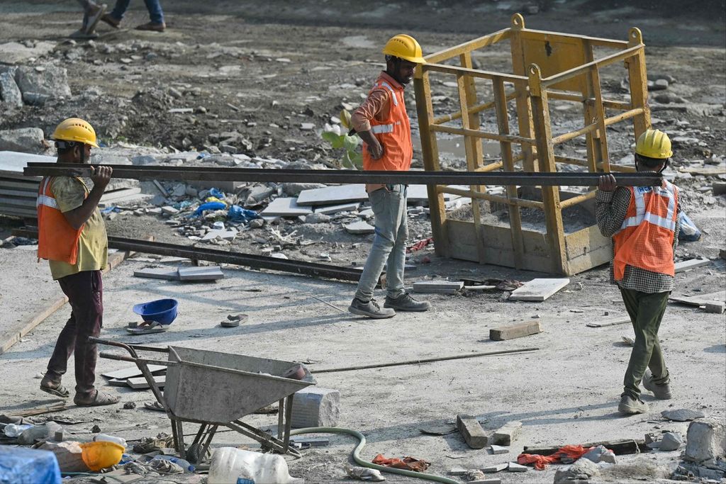 Para pekerja membawa bagian perancah besi di lokasi konstruksi di Mumbai pada 1 Maret 2024. Saat ini, pekerjaan bidang profesional di India minim, banyak sarjana bekerja menjadi buruh kasar. 