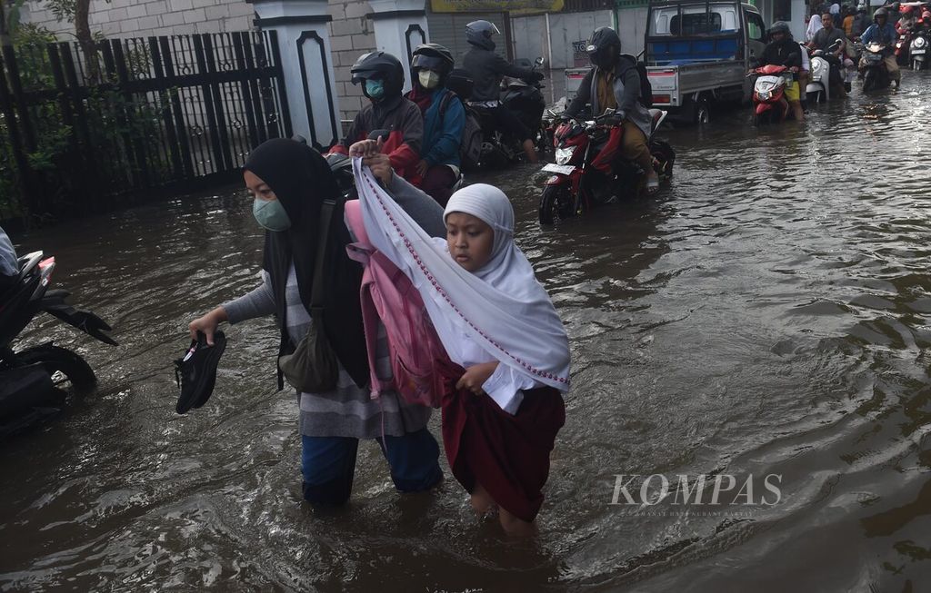 Warga bersama anaknya melewati banjir di Kecamatan Taman, Sidoarjo, Jatim, Selasa (6/2/2024). 