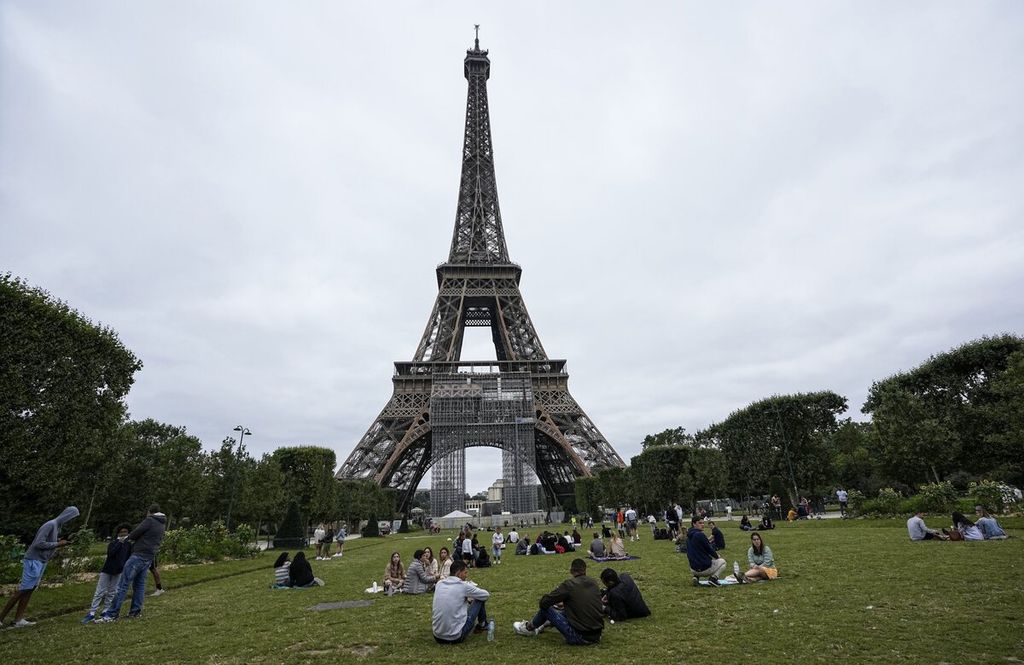 Orang-orang bersantai di Taman Champ-de-Mars di sebelah Menara Eiffel, Paris, Perancis, Jumat (16/7/2021). Kunjungan wisatawan internasional diharapkan bertambah pada 2022 menuju tingkat sebelum pandemi Covid-19.