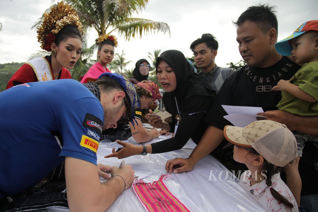 Pebalap Italia, Nicholas Spinelli, membubuhkan tanda tangan pada stiker yang dibawa warga yang hadir dalam Karnaval Budaya Mandalika 2023 di Kuta Mandalika, Kecamatan Pucut, Kabupaten Lombok Tengah, Nusa Tenggara Barat, Rabu (1/3/2023). 