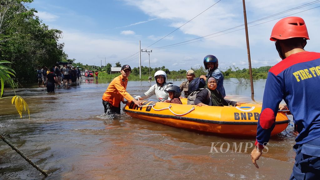 Petugas BPBD Kabupaten Barito Selatan membantu warga yang ingin melintas di titik banjir di Desa Lembeng, Kecamatan Dusun Selatan, Kabupaten Barito Selatan, Kalteng, Kamis (25/1/2024). 