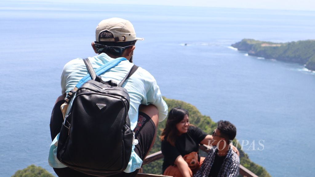 Para pemandu wisata tengah memfoto turis yang dibawanya dengan kamera ponsel, di Pulau Nusa Penida, Kabupaten Klungkung, Bali, Rabu (23/3/2022).