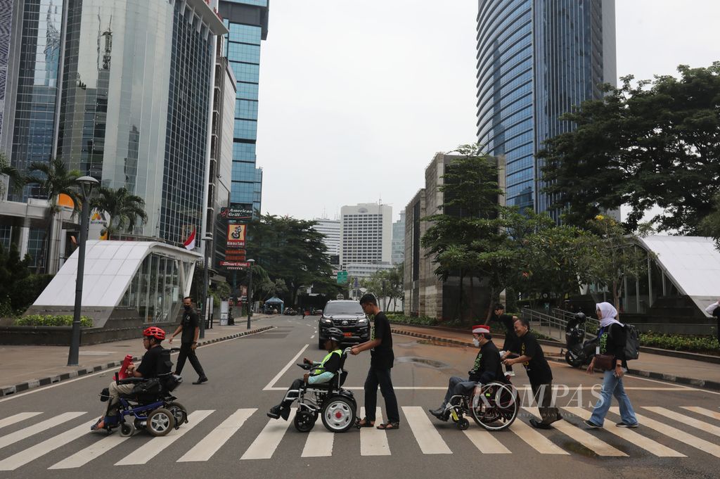 Sejumlah anggota gerakan Penyandang Disabilitas dan Lanjut Usia Indonesia menyeberang di kawasan Dukuh Atas, Jakarta menuju Stasiun MRT saat memperingati Hari Kursi Roda Internasional 2023, Rabu (1/3/2023). 