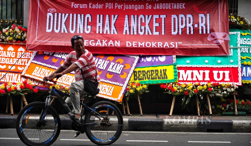 Pengendara sepeda melintasi bagian depan Kantor DPP PDI-P di Jalan Diponegoro, Jakarta, yang dipenuhi karangan bunga dan spanduk desakan penggunaan hak angket oleh PDI-P di DPR, Jumat (8/3/2024).