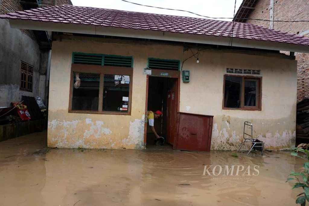 Seorang warga di Kelurahan Kalibalau Kencana, Kecamatan Kedamaian, Kota Bandar Lampung, Lampung, membersikan rumahnya yang terendam banjir, Rabu (23/5/2018). Banjir akibat luapan Sungai Way Balau terjadi setelah hujan deras mengguyur daerah tersebut lebih dari enam jam.