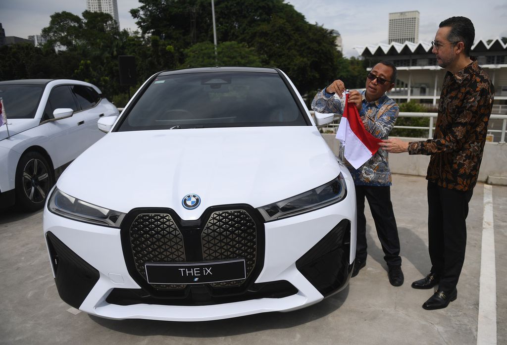 Sekretaris Kementerian Sekretariat Negara (Kemensetneg) Setya Utama (kiri) memasang bendera merah putih dibantu President Director of BMW Group Indonesia Ramesh Divyanathan (kanan) usai acara serah terima mobil resmi KTT ASEAN BMW iX di Jakarta, Kamis (13/4/2023). BMW menyerahkan 13 kendaraan listrik premium BMW iX kepada Kemensetneg untuk digunakan oleh presiden maupun perdana menteri negara peserta KTT ASEAN ke-42 di Labuan Bajo, NTT, 9-11 Mei 2023. 