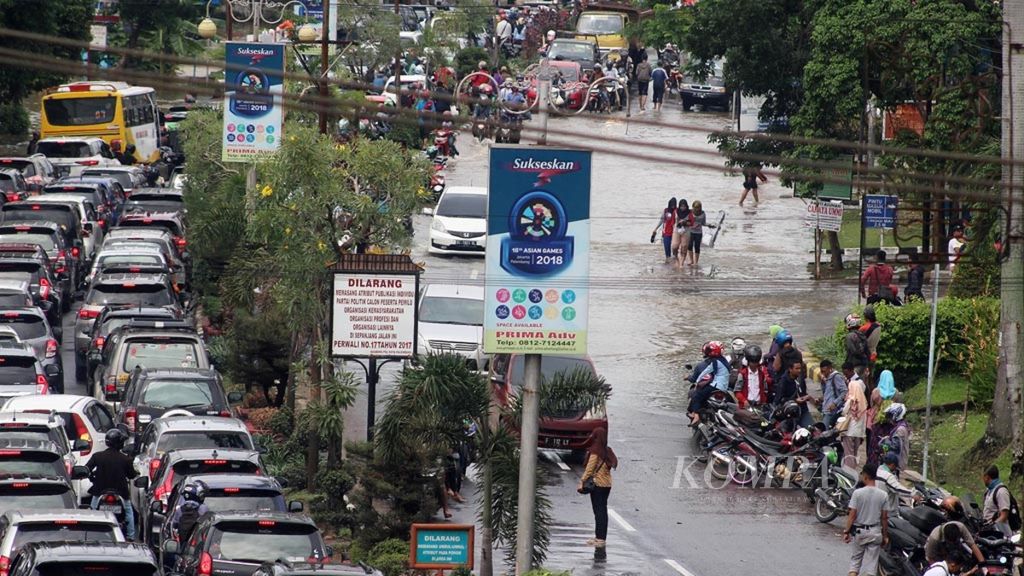 Sejumlah warga berupaya melewati titik banjir yang ada di Jalan R Soekamto, Kota Palembang, Sumsel, Selasa (13/11/2018). Banjir dengan ketinggian 60 sentimeter hingga 2 meter merendam 20 titik kawasan di Palembang. Ini adalah banjir terbesar dalam lima tahun terakhir.