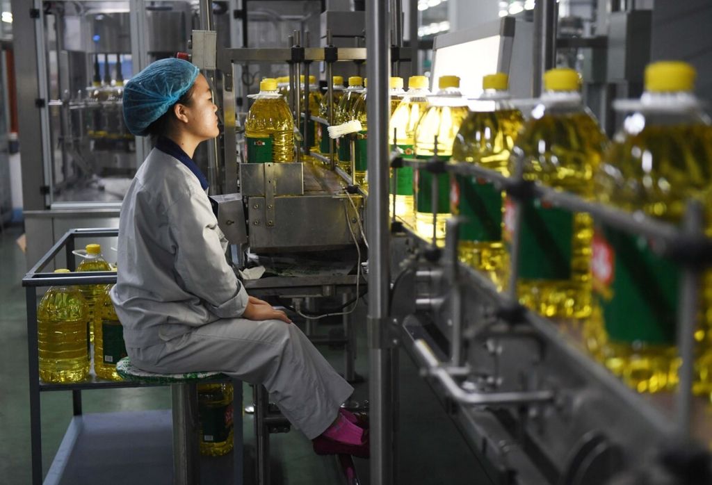 Seorang perempuan pekerja tengah mengawasi produk minyak kedelai di sebuah pabrik di Sanhe, China, Juli 2018.