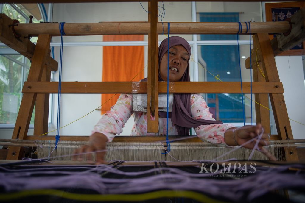 Suhana mengatur benang saat menenun di Pulau Ngenang, Kota Batam, Kepulauan Riau, Kamis (14/12/2023).