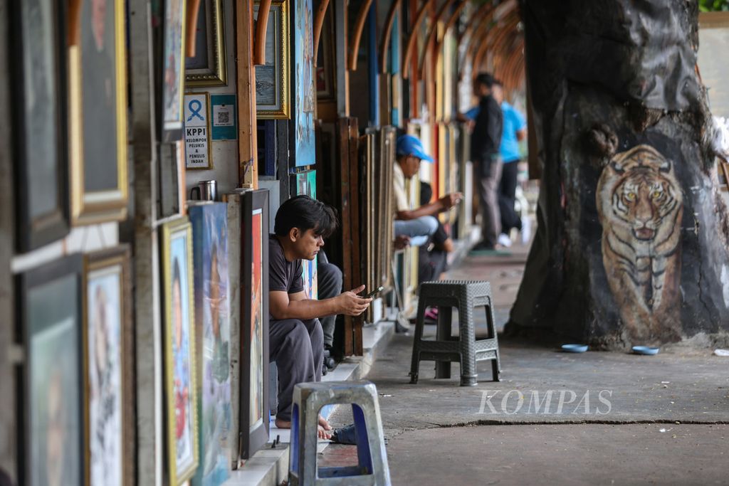 Seorang pelukis menunggu pelanggan di salah satu kios di Jalan Gedung Kesenian, Kecamatan Sawah Besar, Jakarta Pusat.