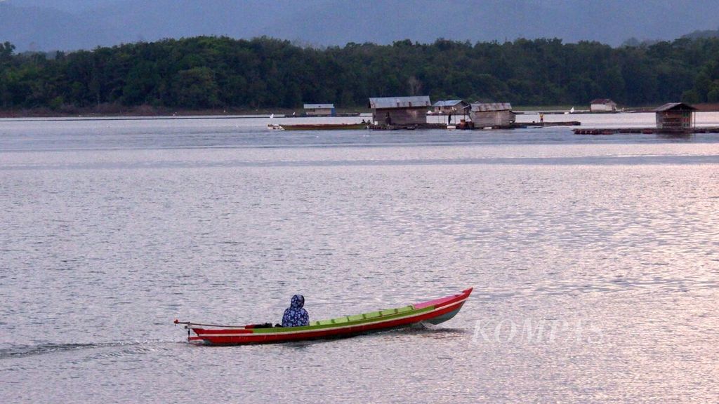 Warga menggunakan kelotok (perahu bermotor) menuju rumah lanting tempat budidaya ikan dalam keramba jaring apung di Waduk Riam Kanan, Desa Benua Riam, Kecamatan Aranio, Kabupaten Banjar, Kalimantan Selatan, Sabtu (28/5/2022).